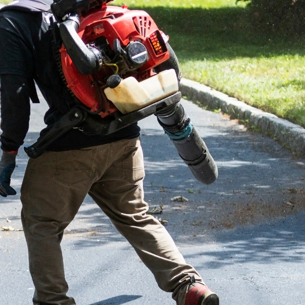 A service technician uses a leaf blower to remove loose dirt and debris from an area to be cleaned.