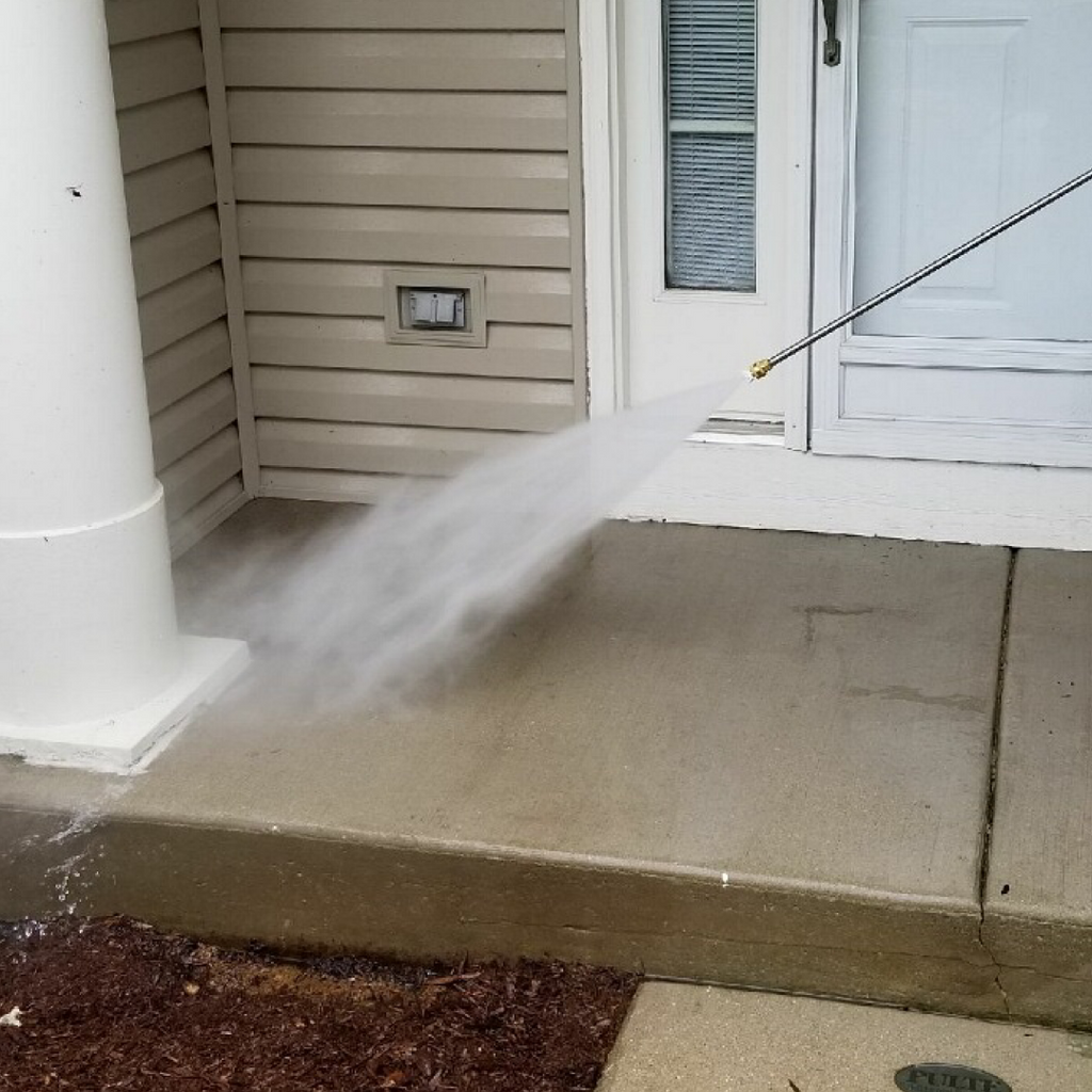 A wand that sprays water is used to rinse of a concrete front stoop that has just been cleaned.
