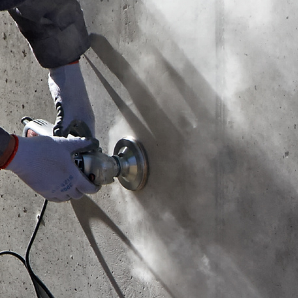 A concrete grinder is being used by a service technician to clean a foundation wall crack to prepare for injection.