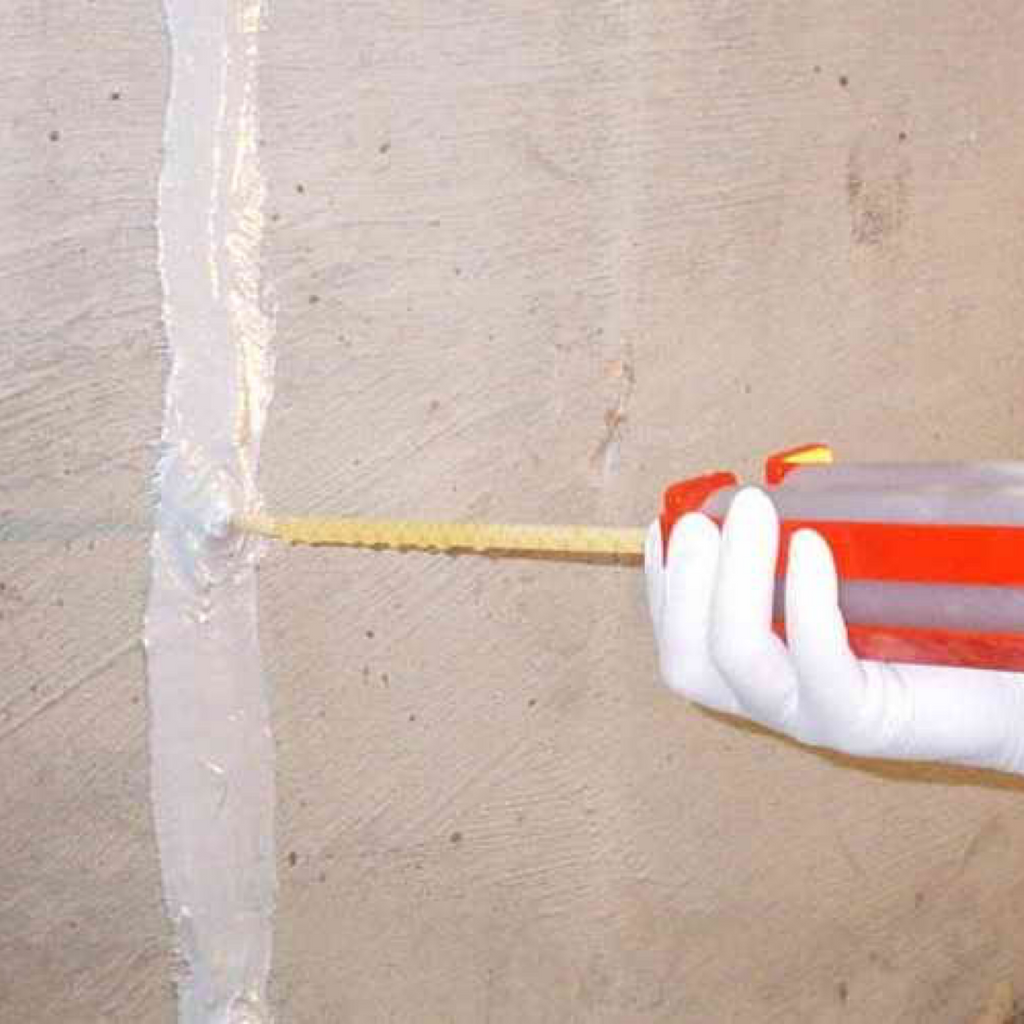 A service technician uses a specialized low pressure caulk gun to inject two-part epoxy through ports placed in a concrete foundation wall to seal the crack.