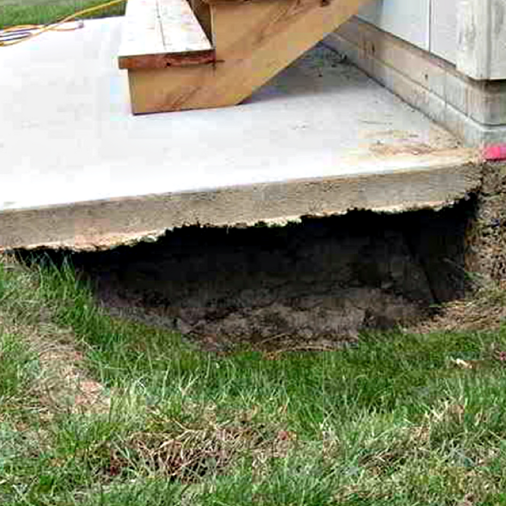 A concrete landing slab is suspended above the ground leaving a large cavity beneath the concrete.