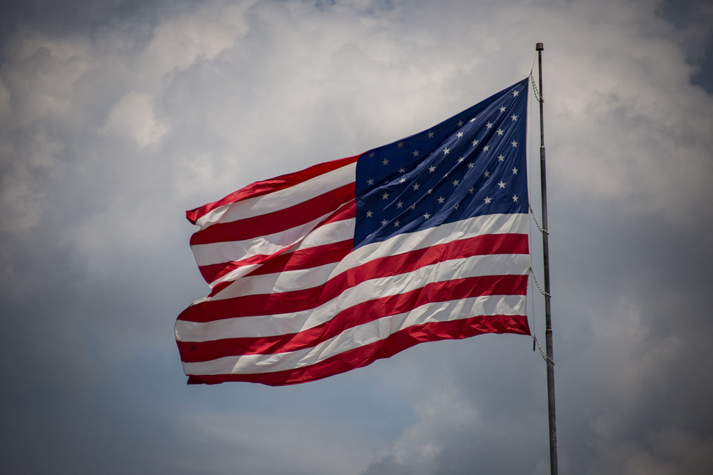 An American flag flying on a flagpole in the wind.